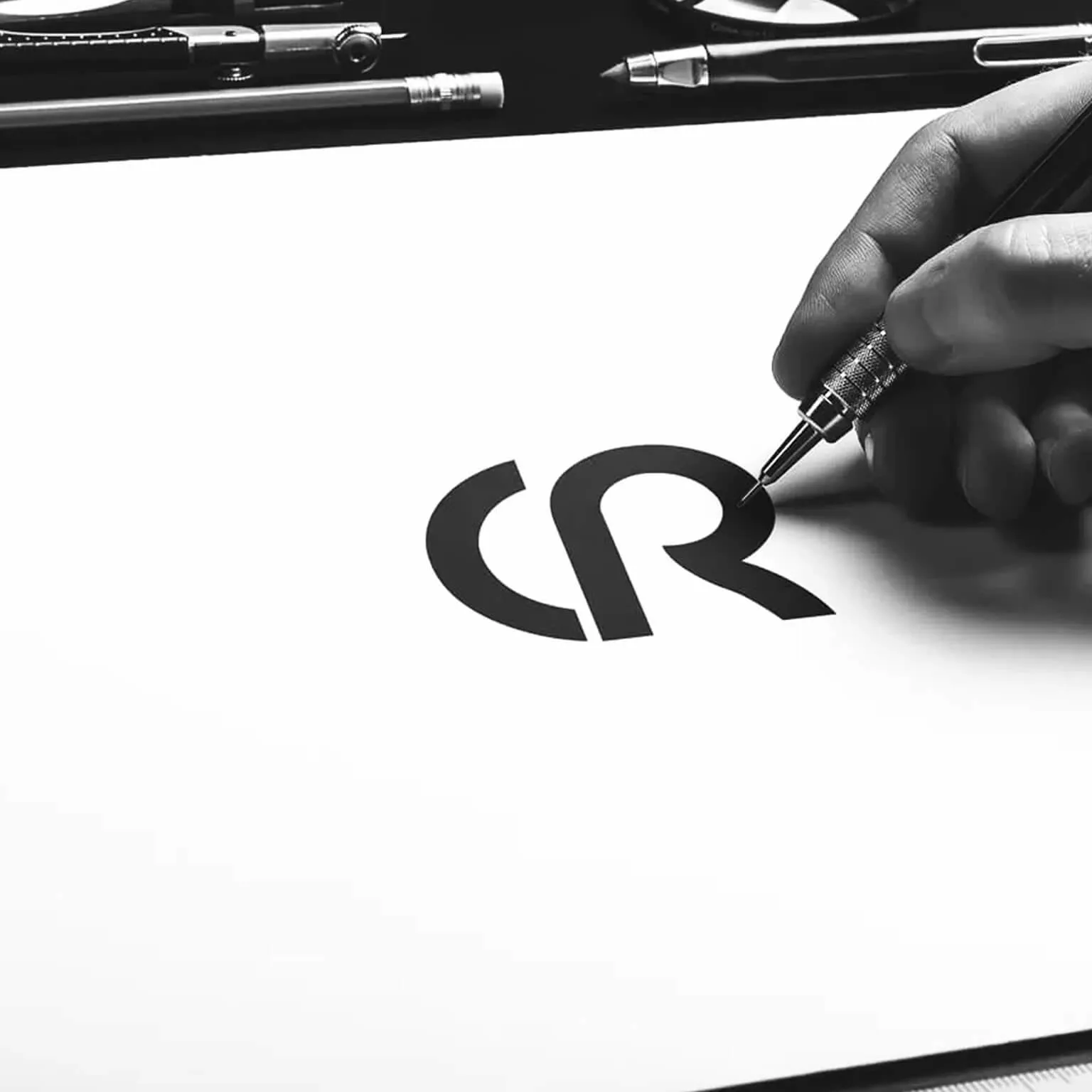 Close-up of the Camelia Ruxandar "CR" logo mark being hand-drawn with a technical pen