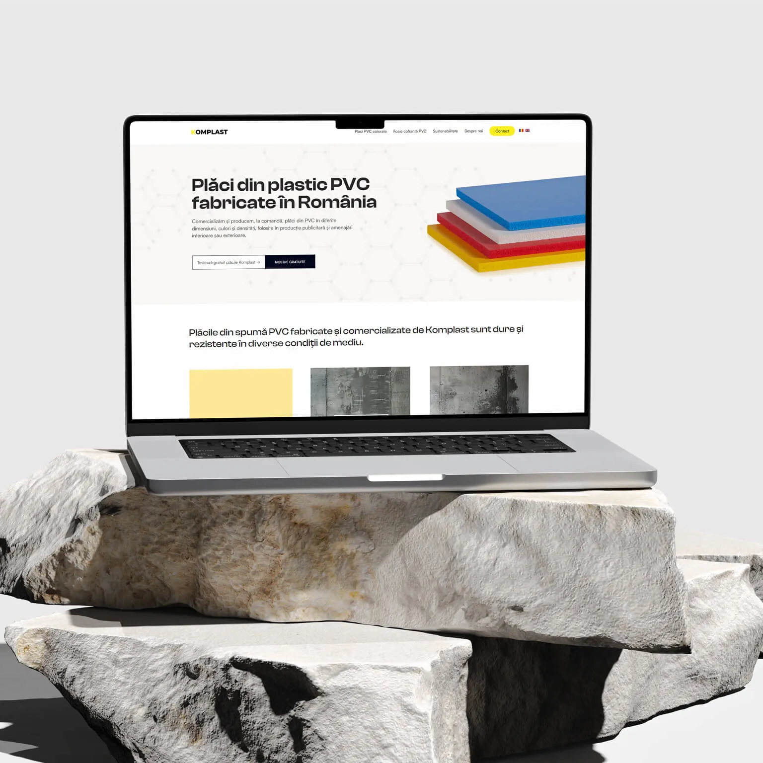 Komplast website homepage on a laptop, showing the colored PVC sheet stack and product hero