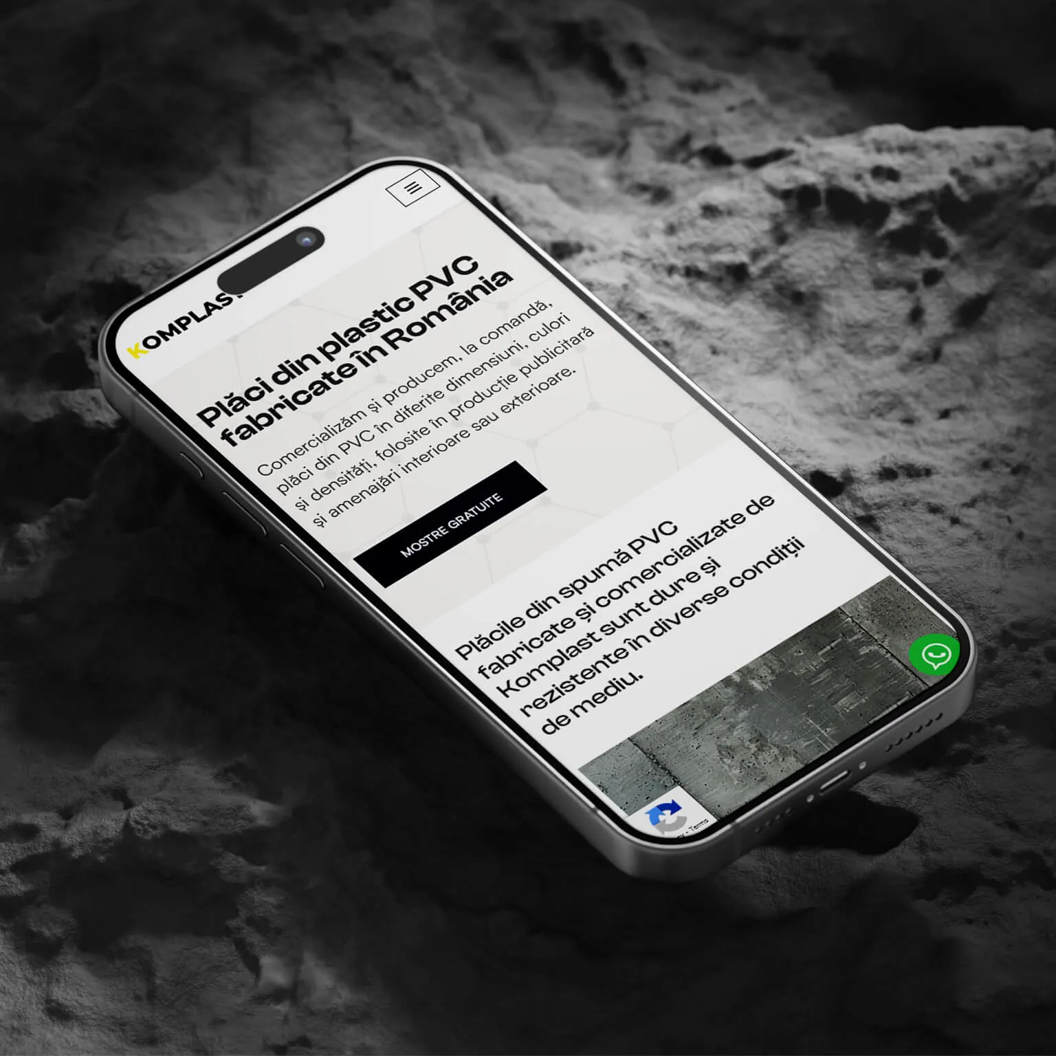 Komplast mobile site homepage on a phone laid on a rock surface